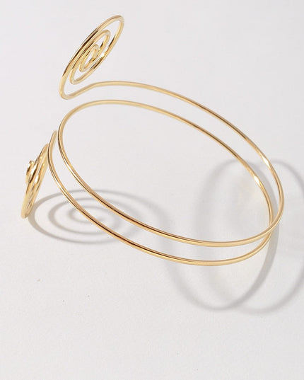 Gold spiral wire arm cuff with double swirl design and open wrap fit

