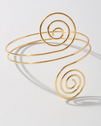 Hypnotic gold arm cuff featuring symmetrical swirl ends and open back

