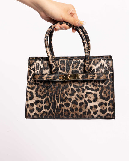 Leopard print handbag with dual top handles and a gold lock, held by hand.
