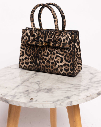 eopard print handbag placed on a marble table, featuring a structured design and gold hardware.