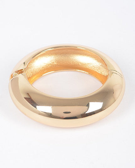 Stacked gold bangles featuring hammered texture and smooth gloss

