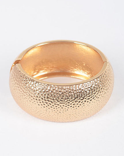 Bold wrist styling with mixed gold bangles in hammered and polished metals

