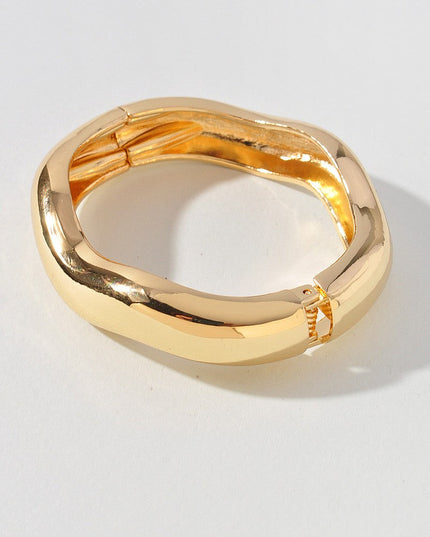 Modern gold-tone bangle featuring spring hinge and bold curved shape

