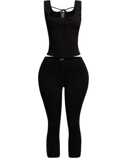 Sleek black tank top with a tie-front detail, paired with fitted capri pants for a modern and edgy outfit.