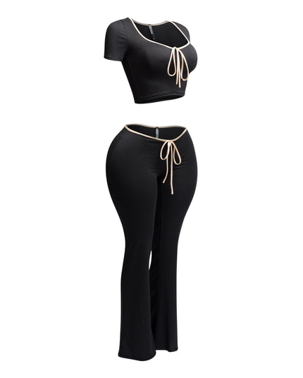 Side view of black and nude trim two-piece set with a tie-front crop top and high-waisted flared pants.