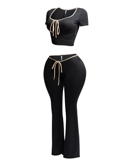 Side view of black and nude trim two-piece set with a tie-front crop top and high-waisted flared pants.